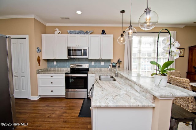 kitchen with sink, white cabinetry, stainless steel appliances, light stone countertops, and decorative light fixtures