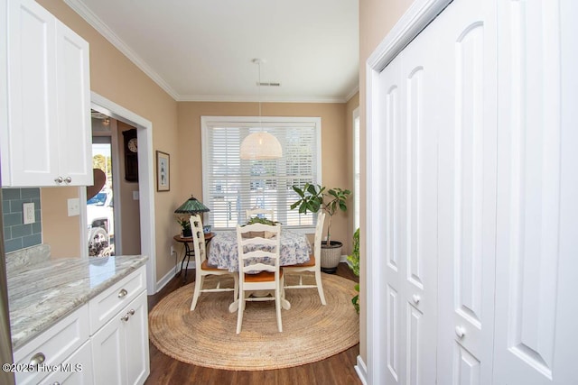 dining area with crown molding and dark wood-type flooring