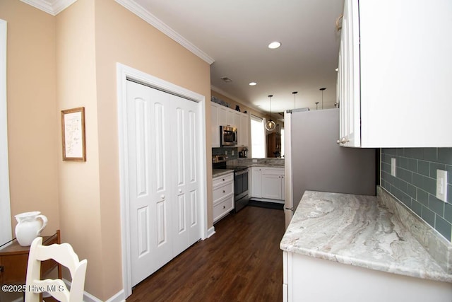 kitchen featuring dark wood-type flooring, appliances with stainless steel finishes, light stone counters, white cabinets, and decorative light fixtures