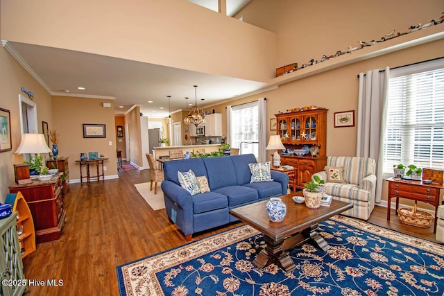 living room with crown molding, dark wood-type flooring, a chandelier, and a healthy amount of sunlight