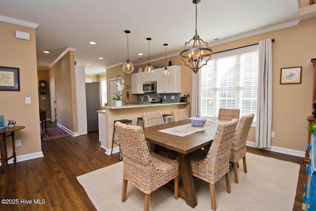 dining area with dark wood-type flooring, ornamental molding, and an inviting chandelier