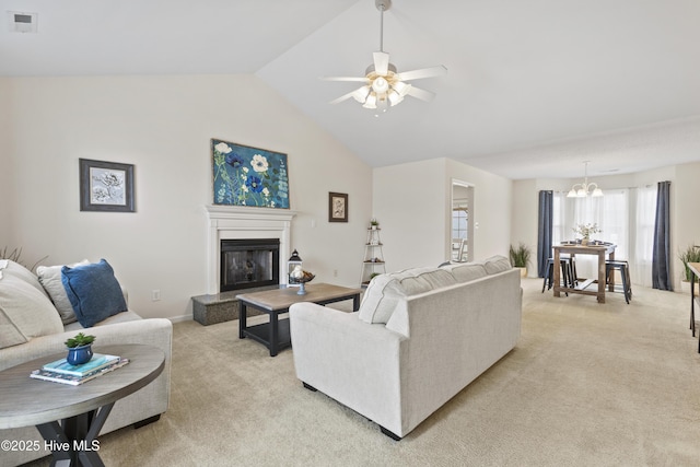 living room with ceiling fan with notable chandelier, vaulted ceiling, and light carpet