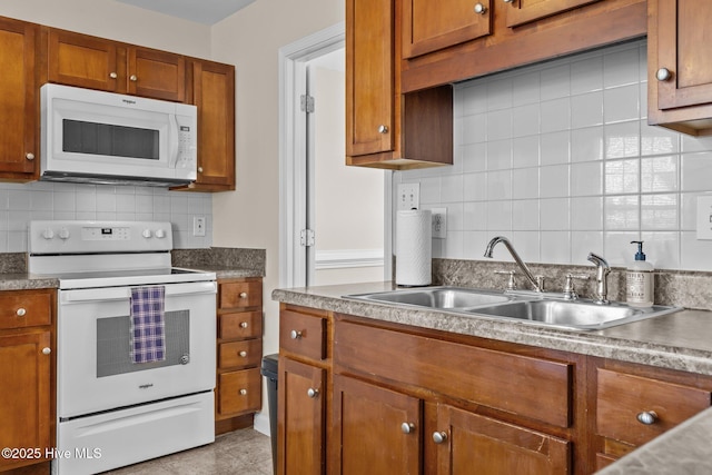 kitchen featuring white appliances, brown cabinets, backsplash, and a sink