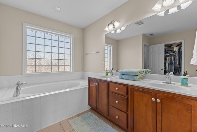 full bathroom with double vanity, a garden tub, tile patterned flooring, and a sink