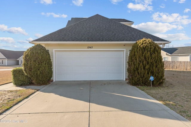 view of home's exterior with concrete driveway, fence, a shingled roof, and a garage