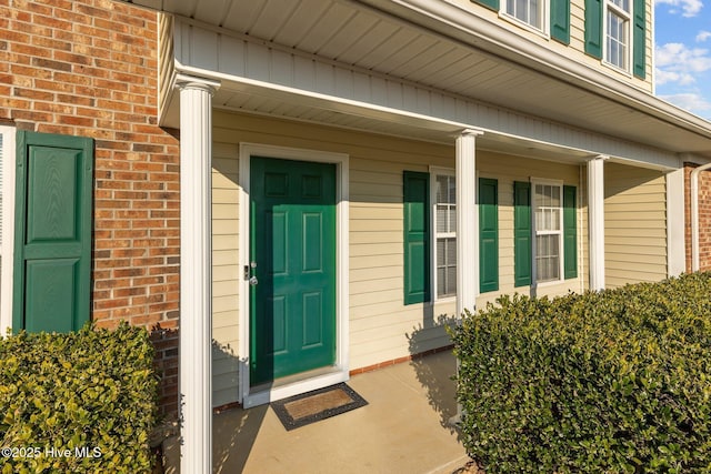 property entrance with covered porch and brick siding