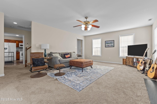 living area featuring baseboards, visible vents, ceiling fan, and light colored carpet