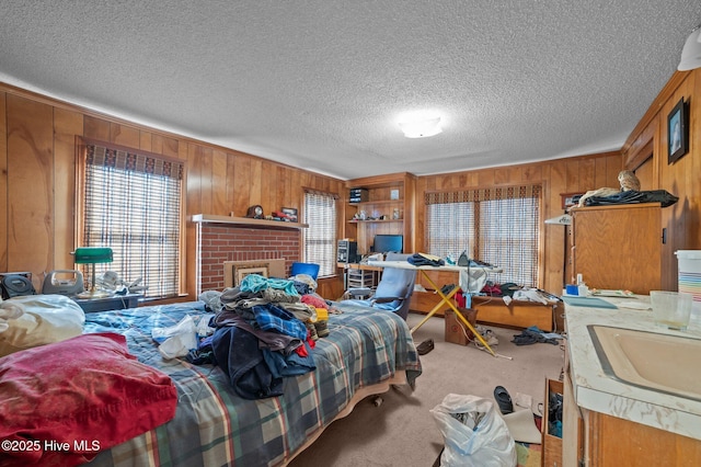 carpeted bedroom with wooden walls, sink, a brick fireplace, and a textured ceiling