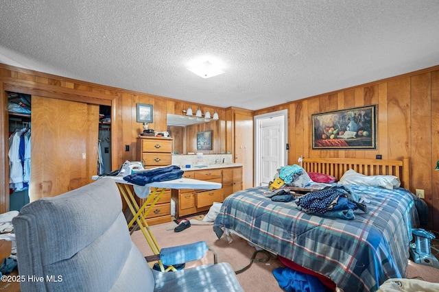 bedroom featuring wood walls, a textured ceiling, and carpet flooring