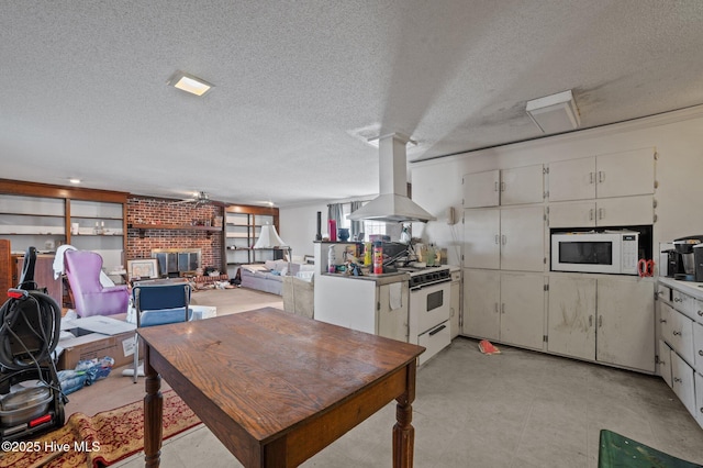 kitchen with island exhaust hood, a brick fireplace, white cabinets, and white appliances