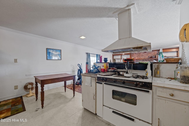 kitchen with white gas range, white cabinets, island exhaust hood, ornamental molding, and a textured ceiling