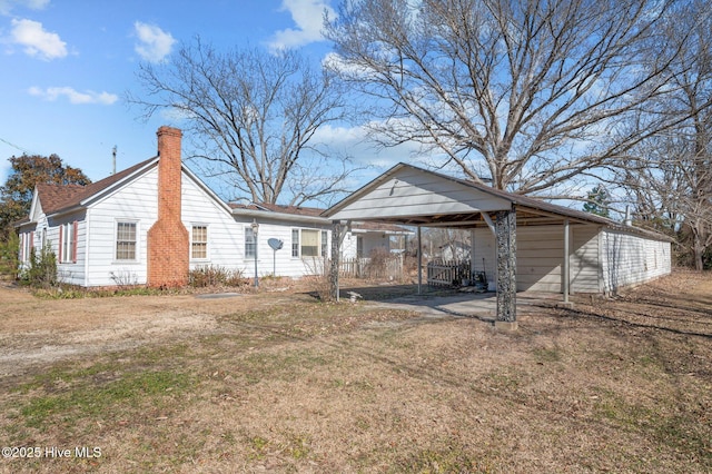 rear view of property with a carport and a yard