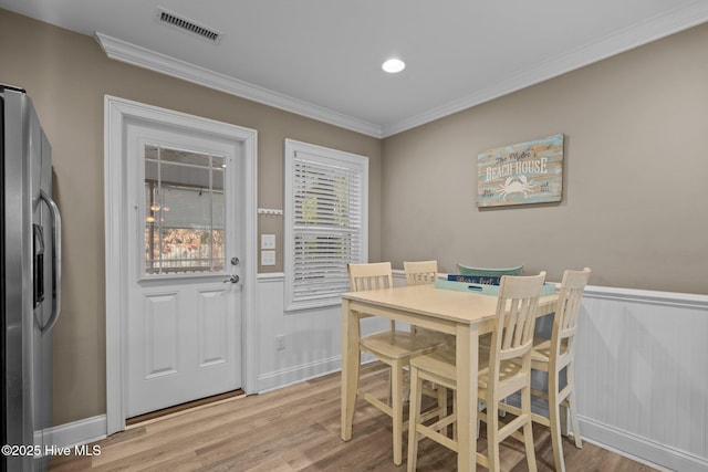 dining space featuring ornamental molding and light wood-type flooring