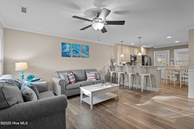 living room with crown molding, ceiling fan, and light hardwood / wood-style floors