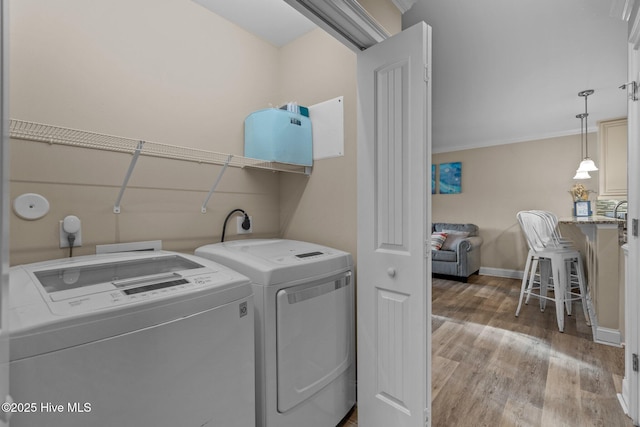 laundry room featuring hardwood / wood-style flooring, ornamental molding, and washer and clothes dryer