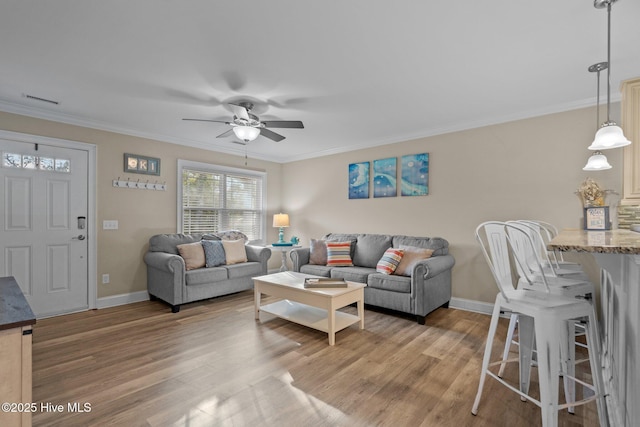 living room with wood-type flooring, ornamental molding, and ceiling fan