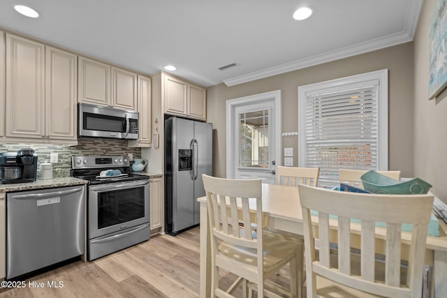 kitchen featuring stainless steel appliances, ornamental molding, tasteful backsplash, and cream cabinetry