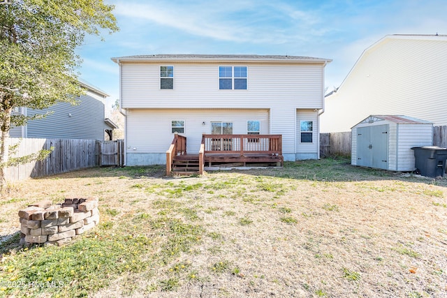 rear view of property featuring a wooden deck, a fire pit, a storage shed, and a yard