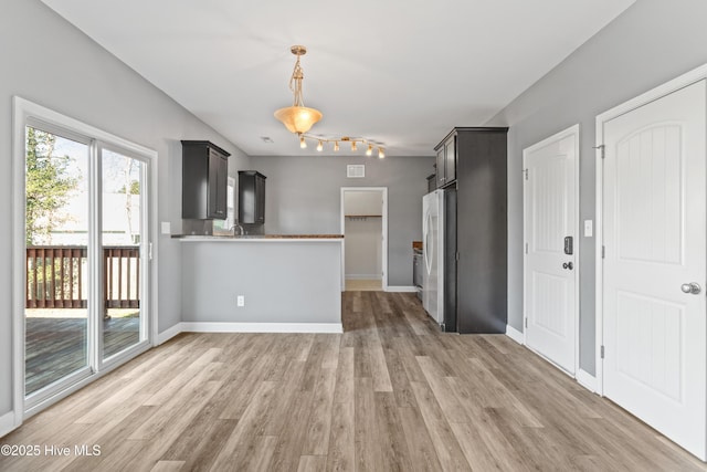 kitchen with stainless steel fridge, light hardwood / wood-style floors, and kitchen peninsula