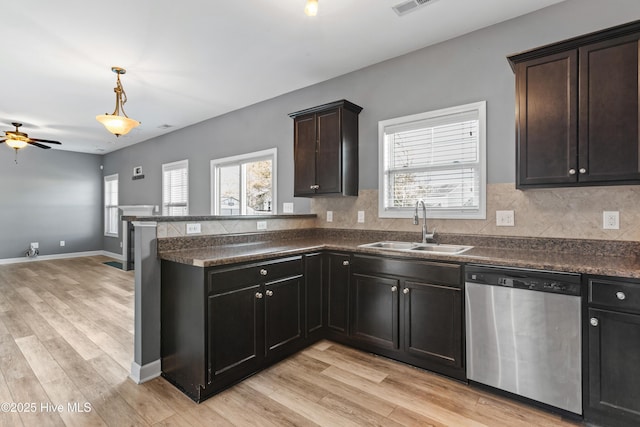 kitchen featuring stainless steel dishwasher, sink, decorative backsplash, and light hardwood / wood-style flooring