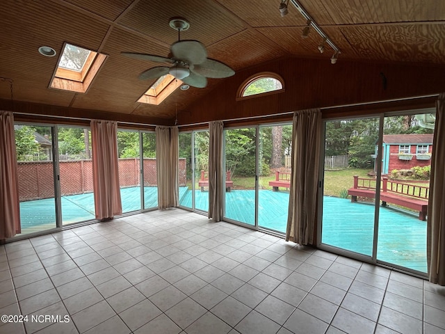 unfurnished sunroom featuring lofted ceiling with skylight, rail lighting, and ceiling fan