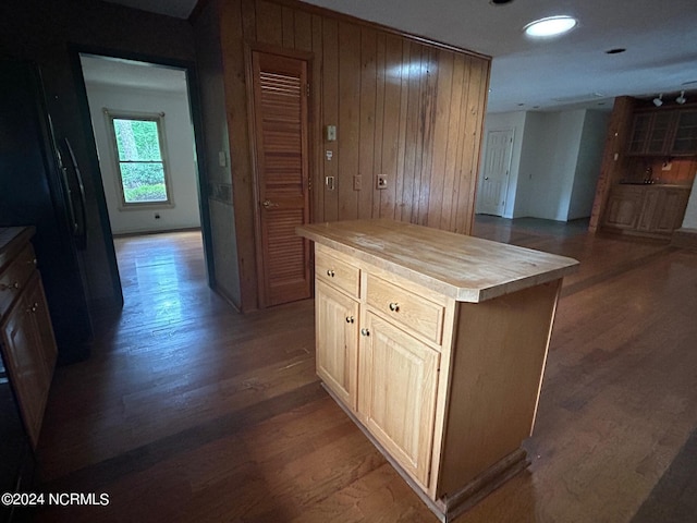 kitchen with black refrigerator, dark hardwood / wood-style floors, a kitchen island, wood counters, and light brown cabinets