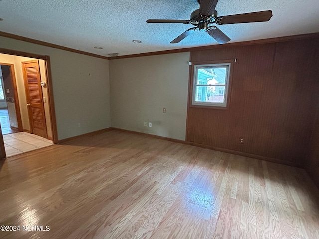 spare room with ornamental molding, a textured ceiling, and light wood-type flooring