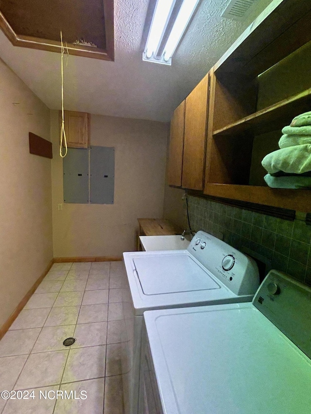 laundry room featuring cabinets, washing machine and clothes dryer, electric panel, and light tile patterned floors