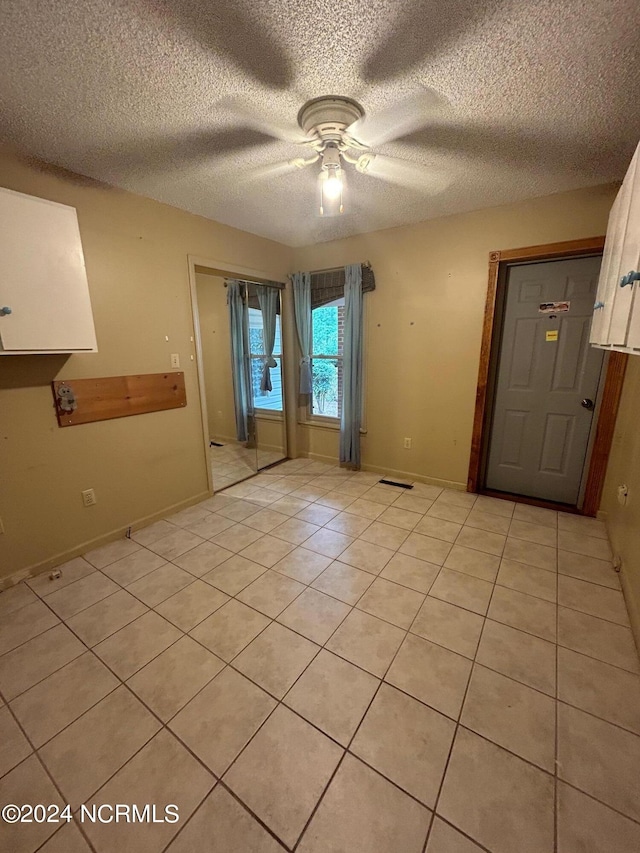 tiled spare room with ceiling fan and a textured ceiling