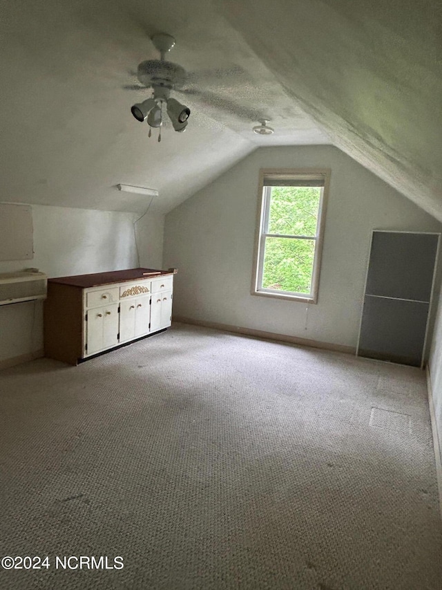 additional living space featuring ceiling fan, lofted ceiling, light carpet, and a textured ceiling