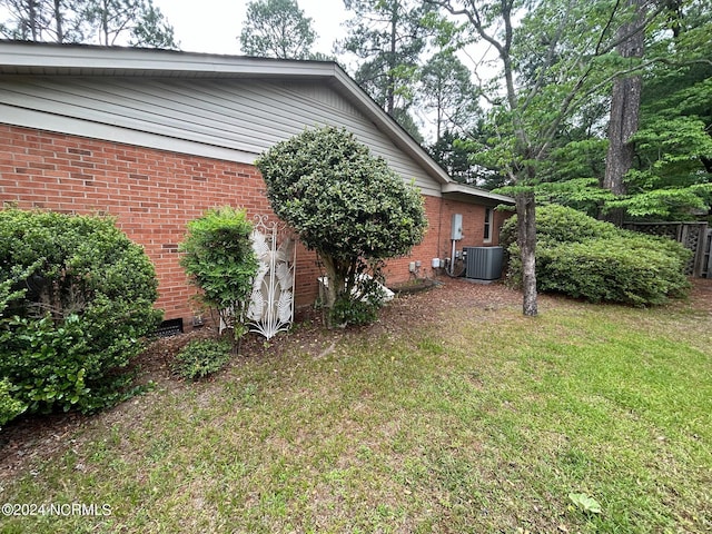 view of side of property with cooling unit and a lawn