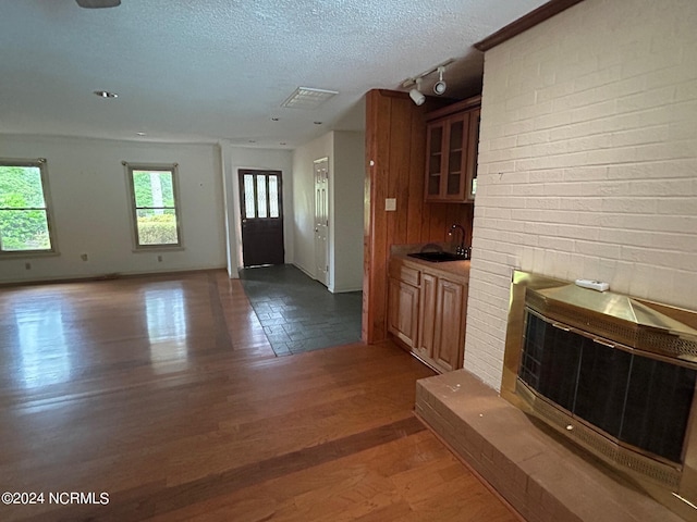 unfurnished living room featuring dark hardwood / wood-style floors, wet bar, and a textured ceiling