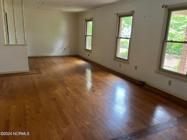 unfurnished room featuring plenty of natural light, ornamental molding, and dark hardwood / wood-style floors