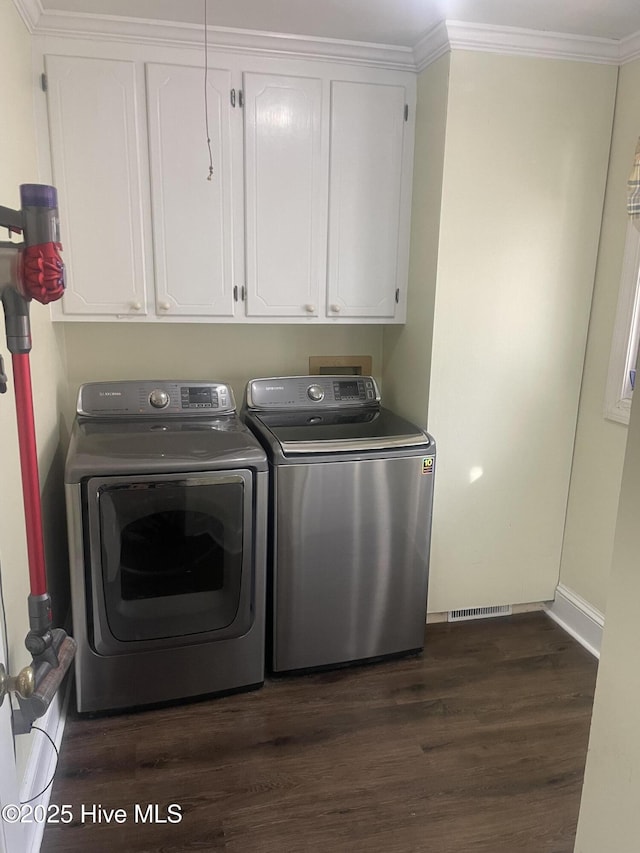 laundry area featuring dark wood finished floors, crown molding, cabinet space, separate washer and dryer, and baseboards