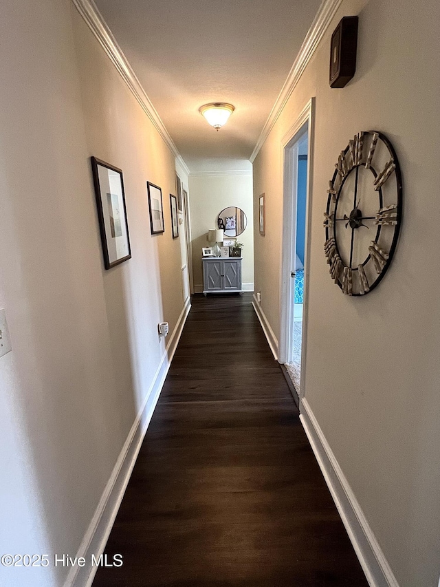 corridor featuring ornamental molding, dark wood-style flooring, and baseboards