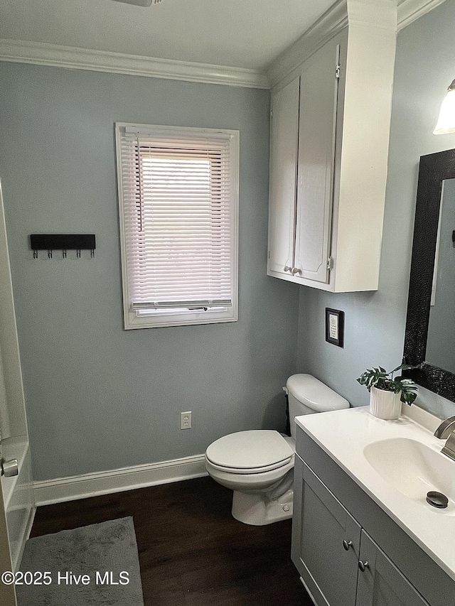 full bathroom with toilet, ornamental molding, vanity, wood finished floors, and baseboards