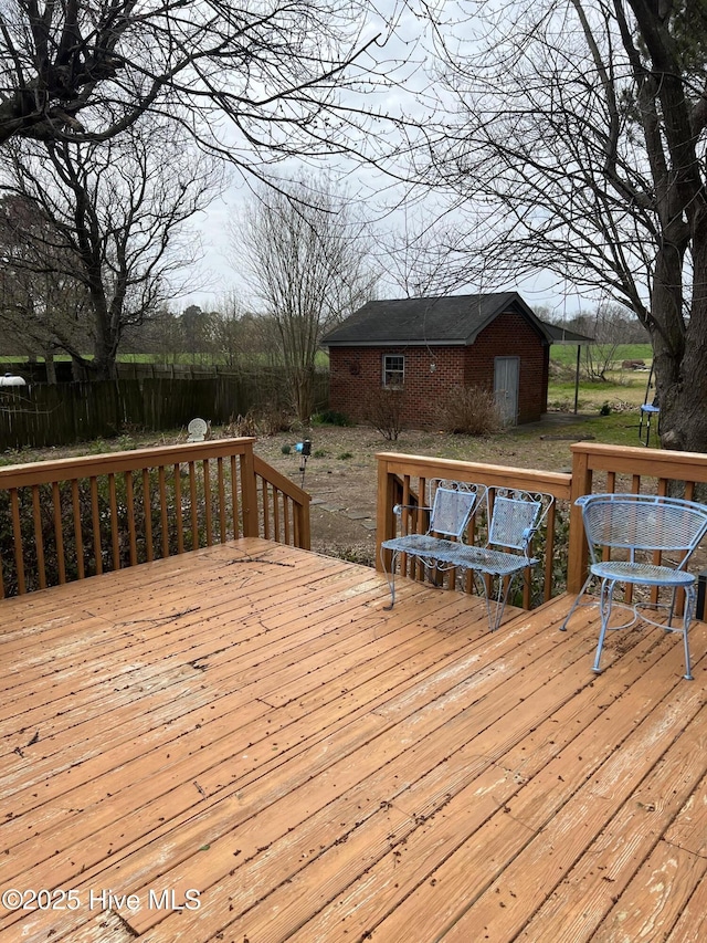 wooden terrace featuring an outdoor structure and fence