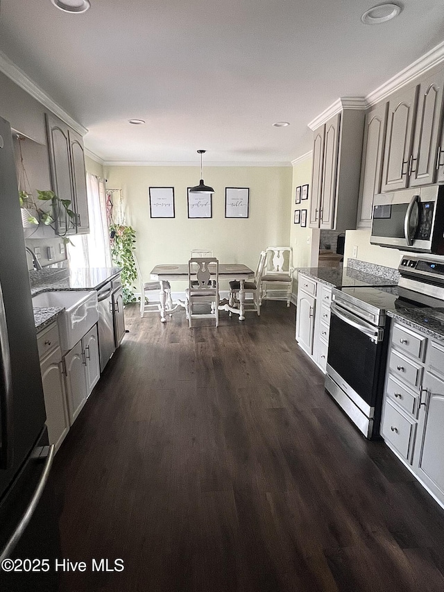 kitchen with dark stone countertops, dark wood finished floors, stainless steel appliances, and crown molding