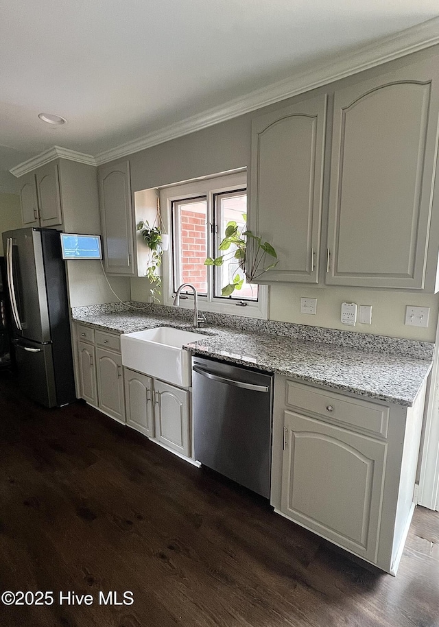 kitchen with stainless steel appliances, dark wood-type flooring, a sink, and light stone counters