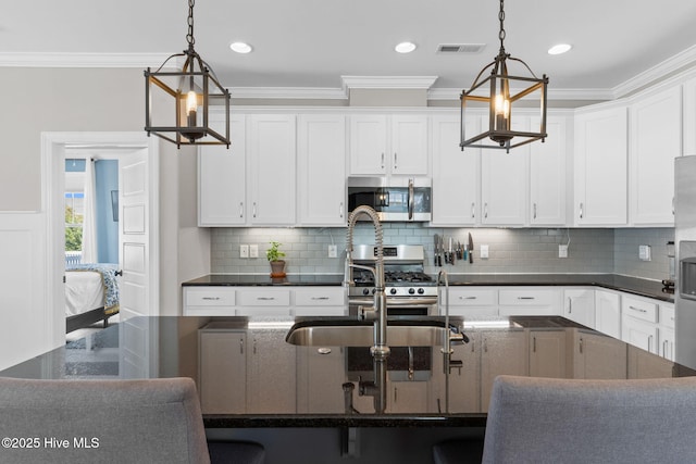 kitchen with stainless steel appliances, hanging light fixtures, white cabinetry, and crown molding