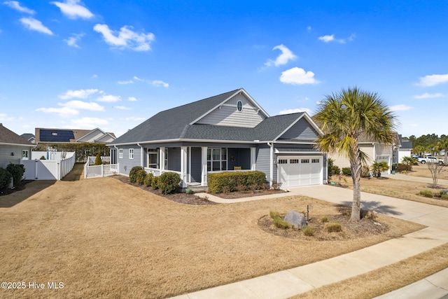 view of front facade featuring roof with shingles, a porch, concrete driveway, an attached garage, and a gate