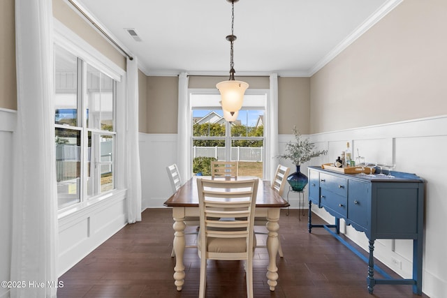 dining space featuring a wainscoted wall, dark wood-style floors, visible vents, and ornamental molding