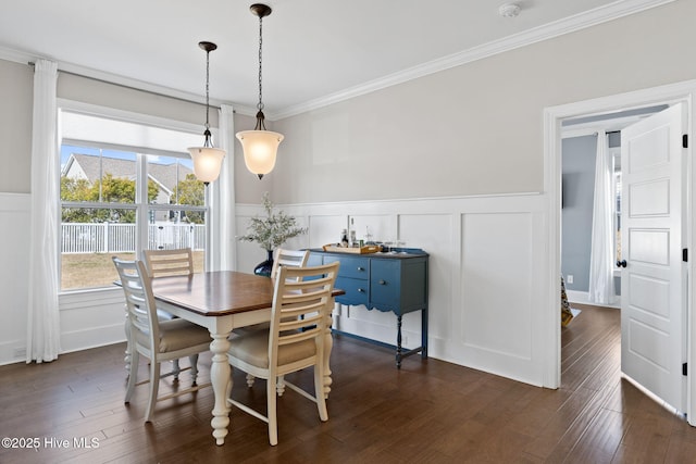 dining space with ornamental molding, dark wood-style flooring, a wainscoted wall, and a decorative wall