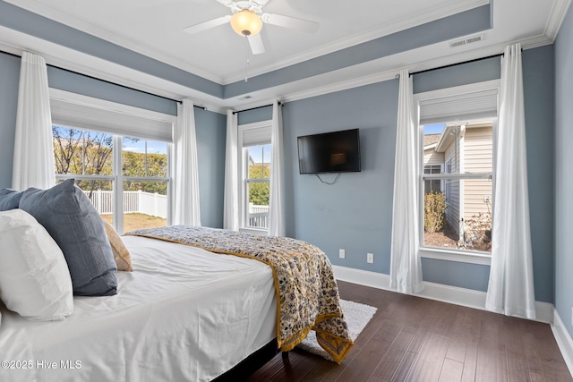 bedroom featuring visible vents, baseboards, a tray ceiling, dark wood finished floors, and crown molding