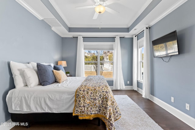 bedroom with dark wood-style flooring, a raised ceiling, ornamental molding, ceiling fan, and baseboards