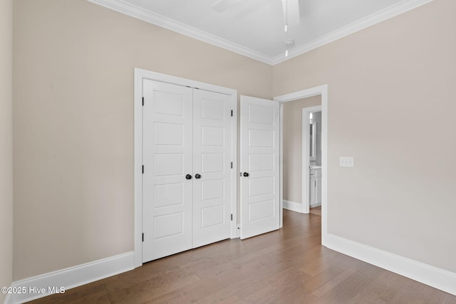 unfurnished bedroom featuring ornamental molding, a closet, wood finished floors, and baseboards