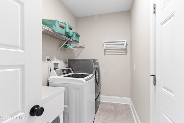 laundry area with light tile patterned floors, laundry area, a sink, baseboards, and washer and clothes dryer