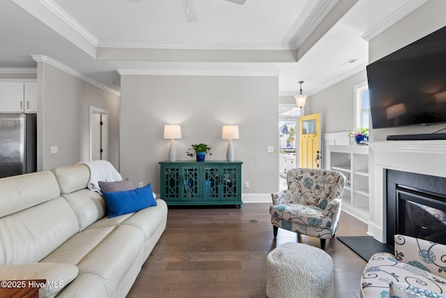 living room with dark wood-style floors, a raised ceiling, and crown molding