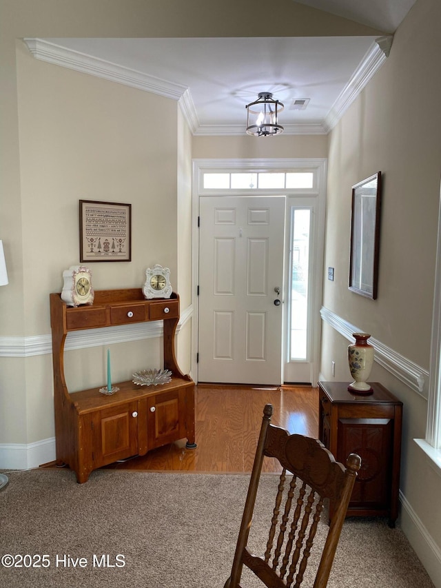 foyer with ornamental molding, a notable chandelier, and light hardwood / wood-style floors