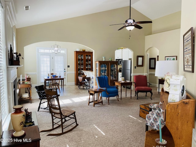 living room with ceiling fan with notable chandelier, high vaulted ceiling, and light carpet